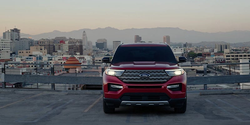 Red 2023 Ford Explorer with headlights facing forward and cityscape behind vehicle