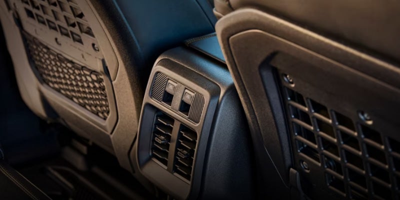 Rear-facing view of a dark car seat with two air vents and two buttons for rear passengers.