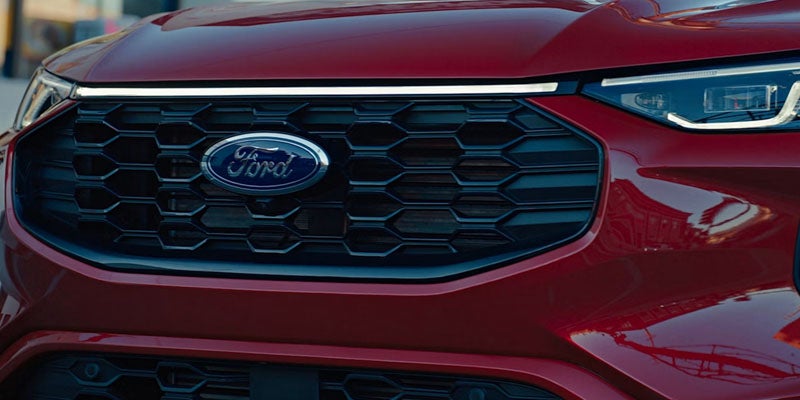 Front view of a dark red car with a honeycomb-patterned grill and a blue Ford logo at its center.