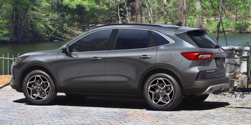 Gray Ford Escape SUV parked on brick next to a lake with trees in the background.
