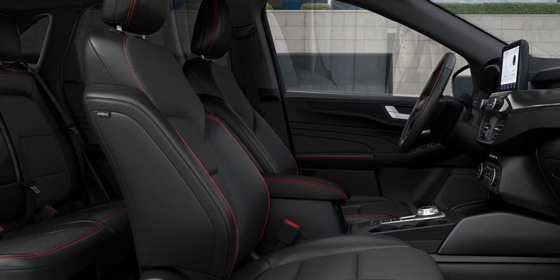 Driver's side interior of a dark grey car with red stitching on seats, steering wheel, and console.
