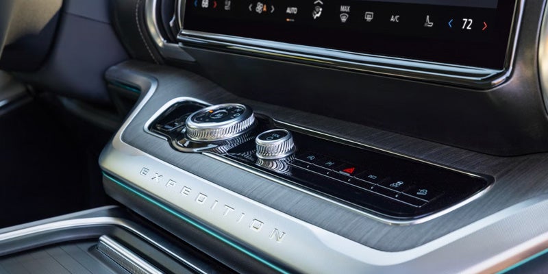 Close-up of a car's center console with climate controls, brushed aluminum trim, and "EXPEDITION" text.