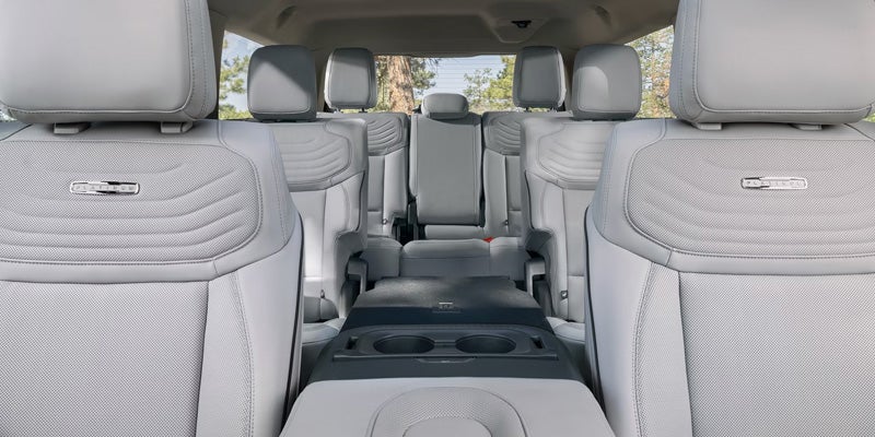 Interior view of a light gray car with three rows of leather seats and "PLATINUM" badges.