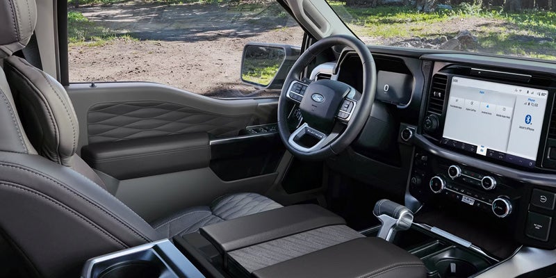 Interior view of a modern truck cabin with black leather seats and steering, a digital dashboard, and a large infotainment screen.