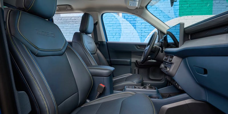 The interior of a blue truck, showing the front passenger and driver seats with yellow accent stitching.