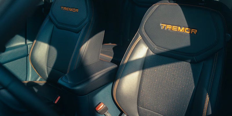 Close-up of truck interior showing two front seats, black leather with "TREMOR" embroidered in orange on headrests.