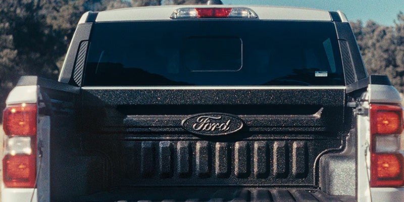 Rear view of a Ford truck with the tailgate open, showing the "Ford" logo molded into the bed liner.