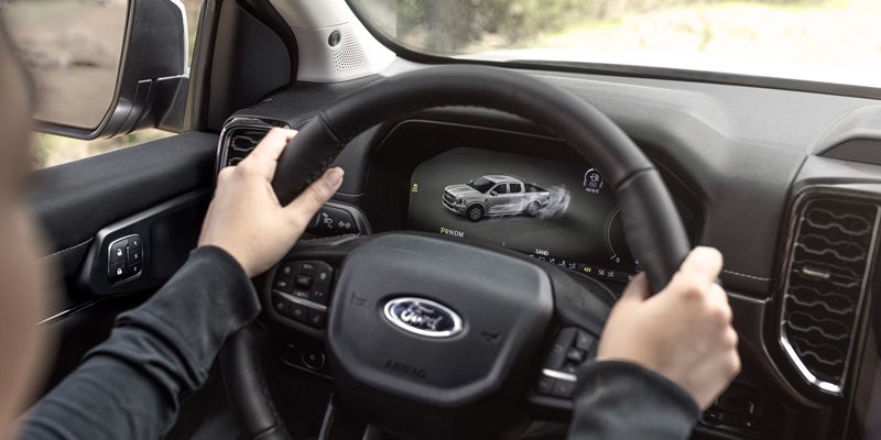 Driver's view of a Ford truck's dashboard screen showing a dynamic graphic of the truck driving through sand.