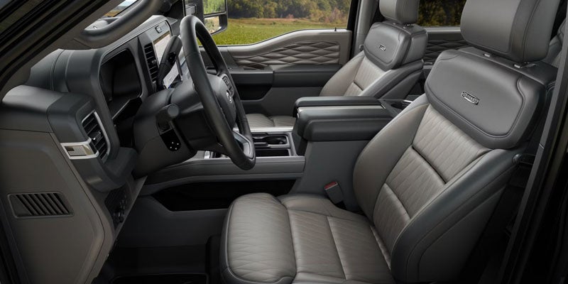 Interior view of a car, showing the driver and passenger seats, dashboard, and steering wheel in muted grey tones.