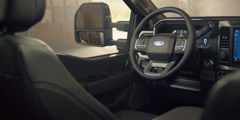 Interior view of a modern truck cabin from the passenger perspective, showing steering wheel and dashboard.