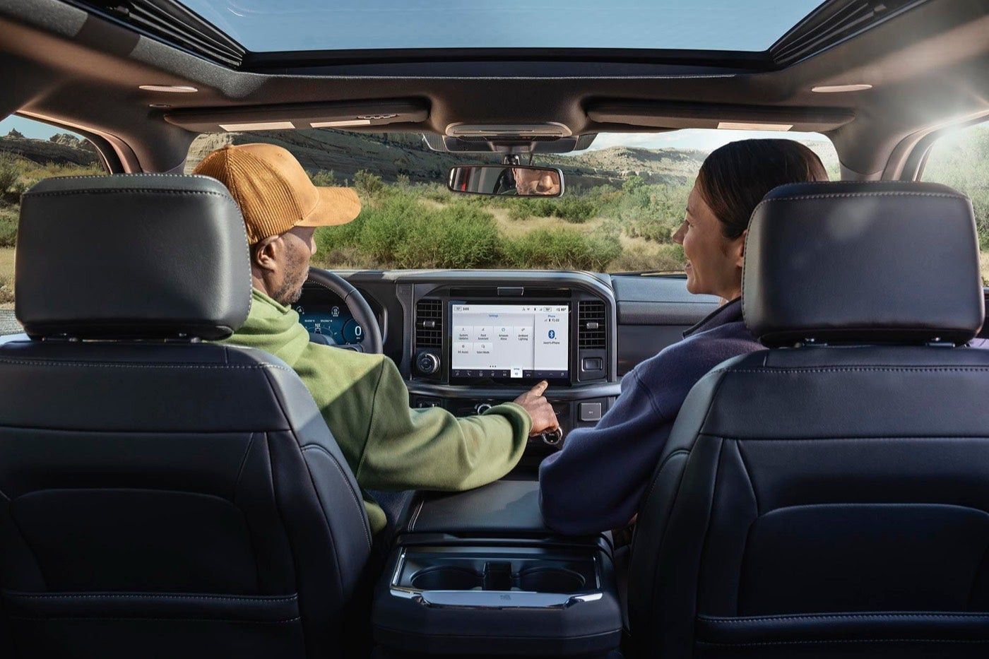 Man using the 12 inch center display in a Ford F-150 with a woman in the passenger seat, shopping for a Ford in Bowie, TX