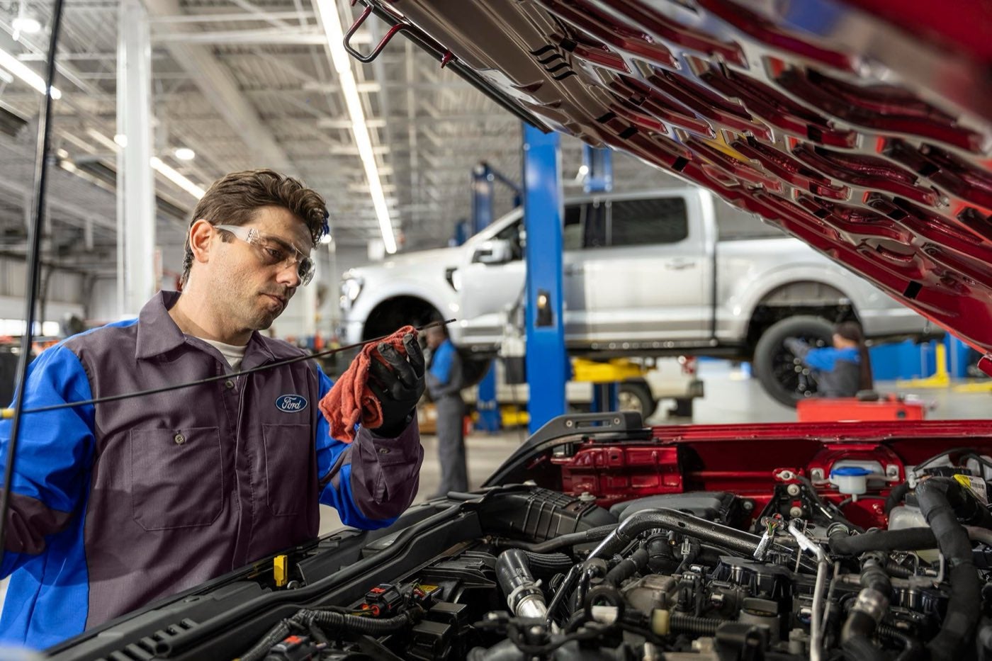 Ford technician working under the hood of a pickup in the service shop, cooling system service in Bowie, TX